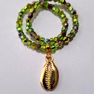 May include: A double strand of green and purple iridescent beads with a gold seashell charm.