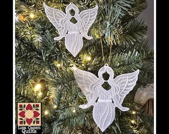 Könnte beinhalten: Zwei weiße Spitzenengel-Ornamente, die an einem Weihnachtsbaum hängen. Die Ornamente sind für Stickmaschinen mit 4x4 und 5x7-Hoop-Größen konzipiert. Der Text "Free Standing Lace - 4x4 & 5x7 Hoop Sizes" befindet sich oben im Bild. Der Text "Lisa Capen Quilts" ist in einem roten und weißen Quiltblock-Design. Der Text "PES, DST, EXP, XXX, JEF, HUS, SEW, VIP, VIP3" befindet sich unten im Bild.