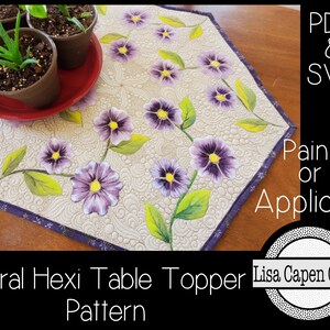 Pode incluir: Um topo de mesa hexagonal com um design floral. O topo de mesa é acolchoado com um padrão em espiral e apresenta flores roxas com centros amarelos e folhas verdes. O texto "Floral Hexi Table Topper Pattern" está na parte inferior da imagem. O texto "PDF & SVG Paint or Applique" está no canto superior direito da imagem. O texto "Lisa Capen Quilts" está em um círculo no canto inferior direito da imagem.
