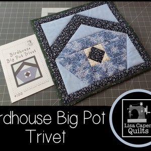 Puede incluir: Un salvamanteles acolchado azul y blanco con un diseño de casa de pájaros. El salvamanteles está etiquetado como "Birdhouse Big Pot Trivet #100".