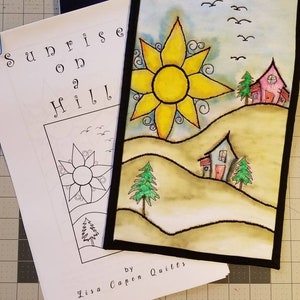 May include: A hand-stitched quilt depicting a sunrise over a hill with two houses and trees. The quilt is titled "Sunrise on a Hill" and is by Lisa Capen Quilts.
