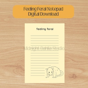 Peut inclure: Un bloc-notes imprimable avec un fond jaune et des lignes noires. Le bloc-notes porte le texte "feeling feral" en haut et une illustration en noir et blanc d'un opossum en bas. Le texte "Midnight Dahlia Studio" est au milieu du bloc-notes.