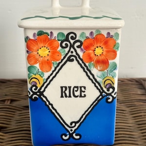 May include: A vintage ceramic rice container with a blue and white diamond pattern and orange flowers. The lid has a white handle and the container says "RICE" in black lettering.