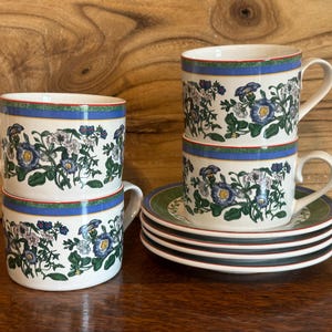 May include: Four floral teacups and saucers with a blue and green floral pattern. The cups are stacked in pairs and the saucers are stacked on top of each other.