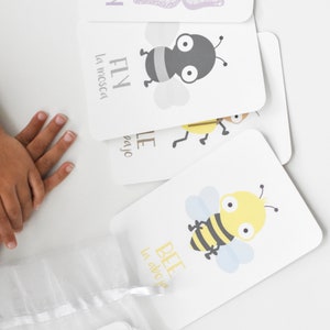 May include: A set of colourful flashcards featuring illustrations of a butterfly, fly, and bee. Each card has the English and Spanish names for the insect. The cards are part of a memory game set by Goodnight Fox.