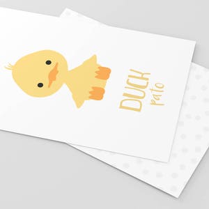 May include: A yellow duckling with orange feet and a black eye is sitting on a white background. The text "DUCH pato" is written in yellow below the duckling.