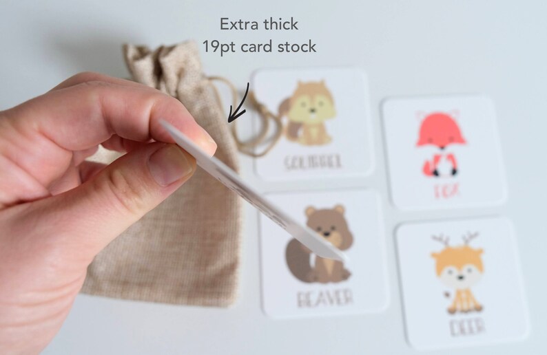 May include: A set of four illustrated animal flash cards with the names "Squirrel", "Fox", "Beaver", and "Deer" printed below each animal. The cards are extra thick, 19pt card stock, and are held in a hand with a small burlap bag in the background.