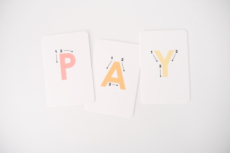 May include: Three white cards with the letters P, A, and Y written in orange, yellow, and pink. Each letter has numbers and arrows indicating the order to trace the letter.