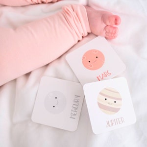 May include: Three illustrated flashcards featuring planets from our solar system. The cards are white with black text and colorful illustrations of Mercury, Mars, and Jupiter. Each planet has a smiling face.