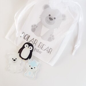 May include: A white organza bag with a white tag that says "Polar Bear" and a cartoon image of a polar bear. The bag contains three small plastic figurines: a penguin, a polar bear, and a fox.