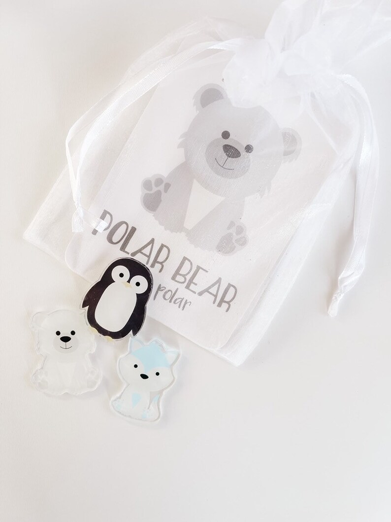 May include: A white organza bag with a white tag that says "Polar Bear" and a cartoon image of a polar bear. The bag contains three small plastic figurines: a penguin, a polar bear, and a fox.