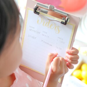 Montessori-inspired toddler activity with lemonade stand printable elements including menu, pricing sign, and decorative lemons to encourage independent play and hands-on summer learning.
