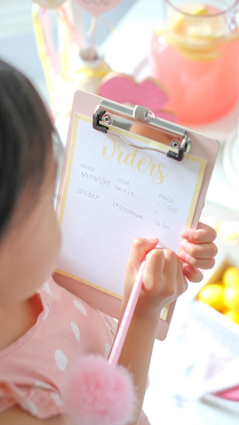 Montessori-inspired toddler activity with lemonade stand printable elements including menu, pricing sign, and decorative lemons to encourage independent play and hands-on summer learning.
