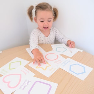 K&ouml;nnte beinhalten: Ein kleines Kind lernt Formen, indem es Karten mit verschiedenen Formen zusammenbringt. Die Karten sind farbcodiert und haben den Formnamen in Englisch und Spanisch darauf geschrieben. Die Formen umfassen ein Herz, einen Stern, ein Quadrat, eine Raute, einen Kreis und ein Sechseck.