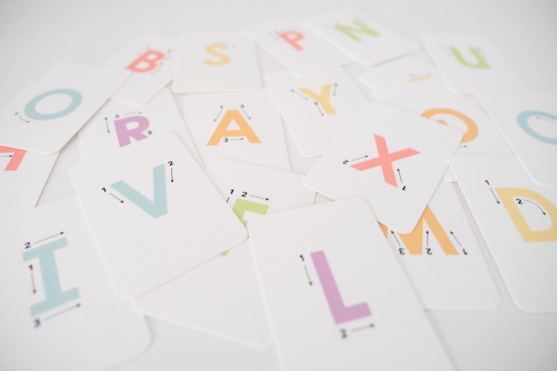 May include: A set of colorful alphabet flash cards with dotted lines and numbers to help children learn to trace letters. The cards are on a white surface.