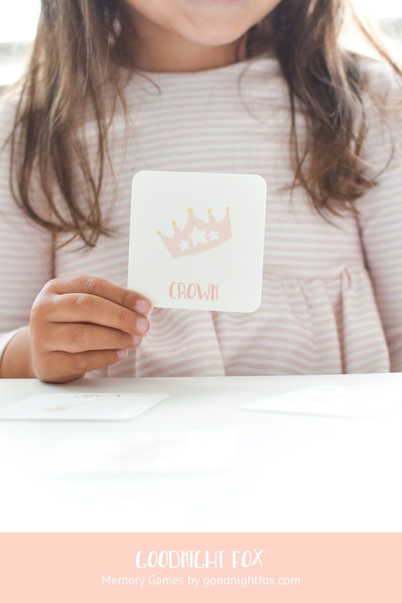 May include: A pink and white card with a gold crown and the word "crown" printed on it. The card is being held by a child.