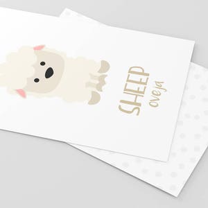 May include: A white sheep with a pink nose and black eyes is illustrated on a white card with the text "SHEEP oveja" in brown lettering.