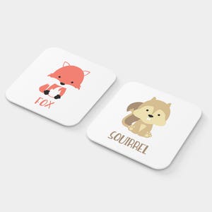 May include: Two white square cards with illustrations of a fox and a squirrel. The fox is orange and the squirrel is brown. The cards have the words "Fox" and "Squirrel" printed on them.