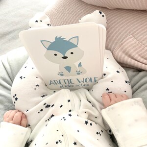 May include: A white book with a blue cartoon arctic wolf on the cover. The book has the text "Arctic Wolf" and "el lobo artico" on the cover.