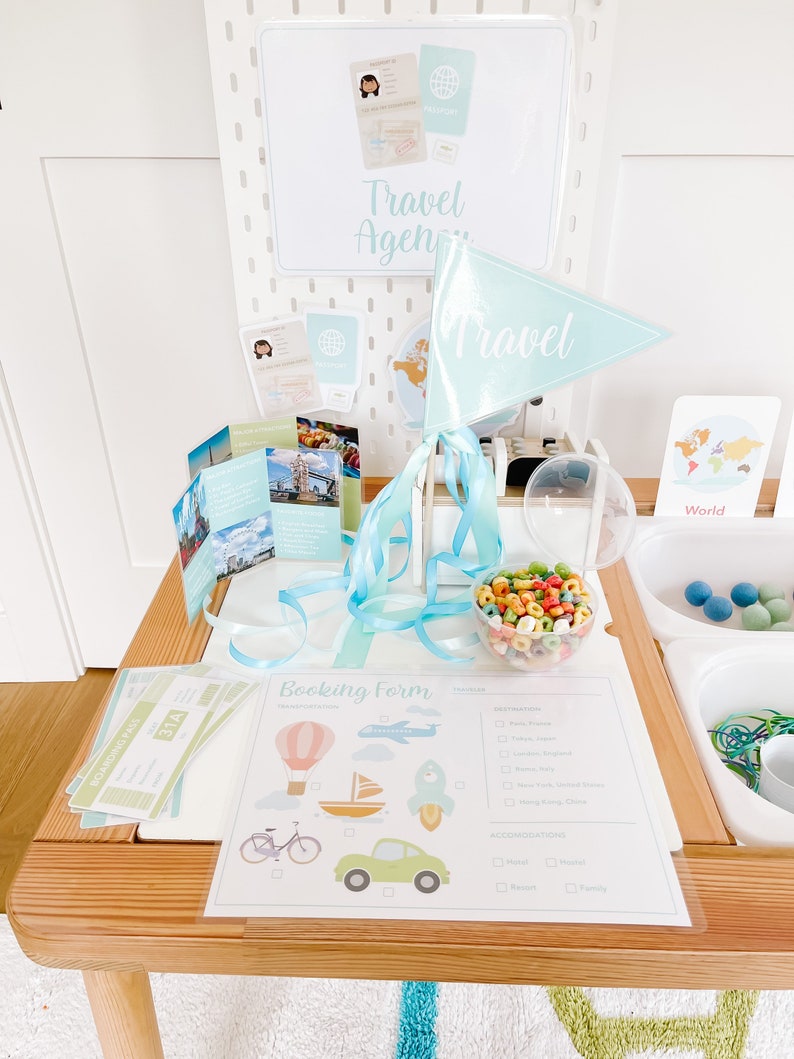 May include: A play set for kids to pretend to be travel agents. The set includes a booking form, tickets, a passport, a world map, and a travel flag. The form has a list of destinations and accommodations.