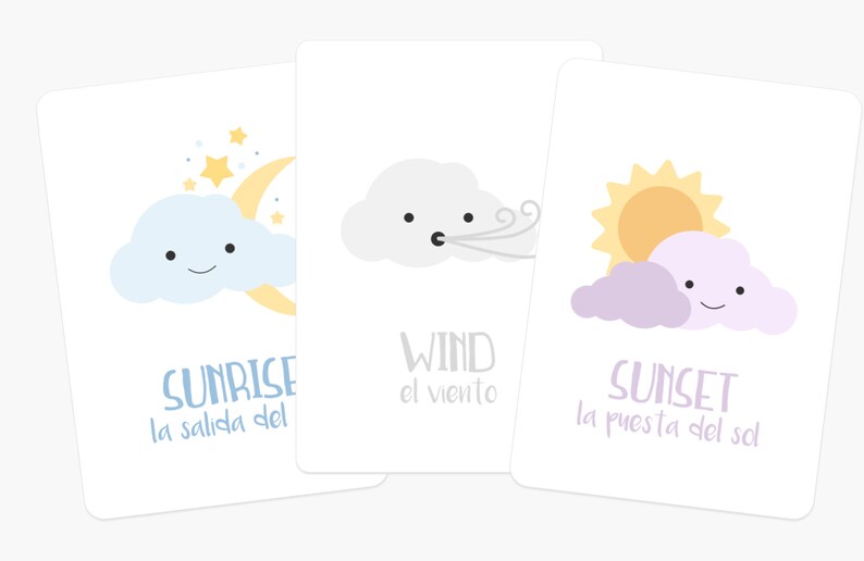 May include: Three illustrated cards with a cartoon cloud and sun or moon. The first card shows a blue cloud with a crescent moon and stars, and the text "Sunrise la salida del". The second card shows a gray cloud with wind blowing, and the text "Wind el viento". The third card shows a purple cloud with a yellow sun, and the text "Sunset la puesta del sol".