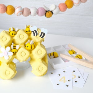 Child using the bee and flower matching activity, sorting bees into corresponding flowers for a pollination game.