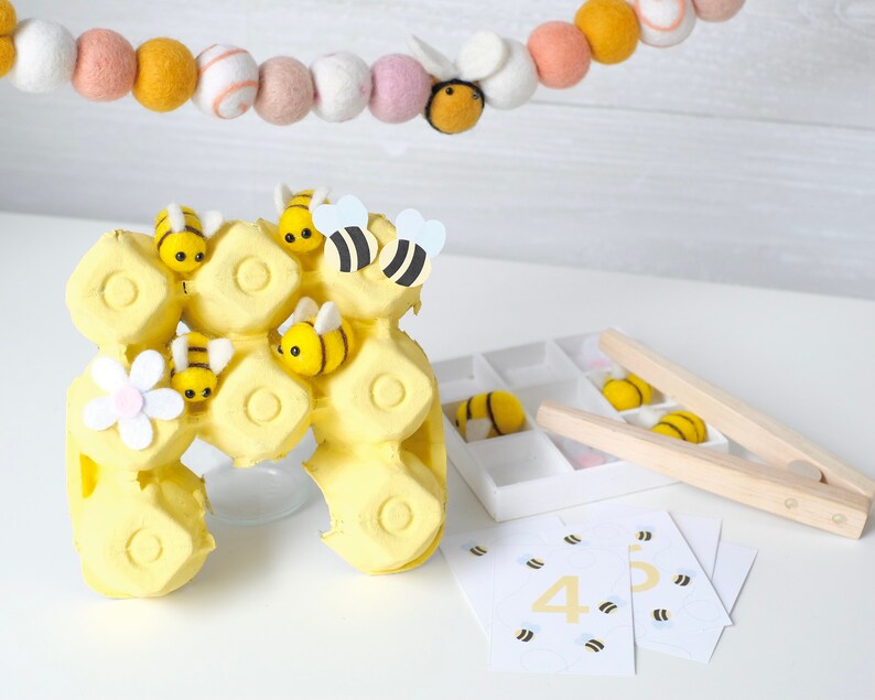 Child using the bee and flower matching activity, sorting bees into corresponding flowers for a pollination game.