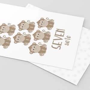 May include: A white card with seven brown monkeys holding sticks. The text "SEVEN siete" is printed on the card.