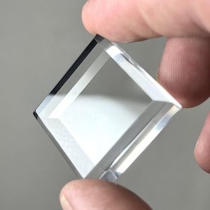 Puede incluir: Un prisma cuadrado de vidrio transparente con bordes biselados.