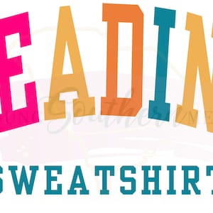 K&ouml;nnte beinhalten: Ein farbenfrohes Grafikdesign mit dem Wort "READING" in einer gro&szlig;en, fetten Schrift. Die Buchstaben sind in verschiedenen Farben: blaugr&uuml;n, pink, orange, blaugr&uuml;n, orange und pink. Unter dem Wort "READING" steht das Wort "SWEATSHIRT" in blaugr&uuml;n.