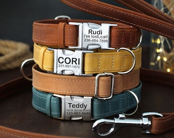 May include: Four leather dog collars with personalized silver tags. The collars are stacked on top of each other, with the top collar being brown, the second collar being yellow, the third collar being tan, and the bottom collar being teal. The tags have the names "Rudi", "Cori", "Teddy", and phone numbers.