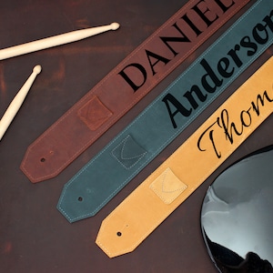 May include: Three leather guitar straps with different colors and personalized names: Daniel, Anderson, and Thomas.