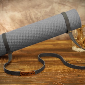 May include: A gray yoga mat with a brown leather strap and a personalized name tag that says "Dominic".