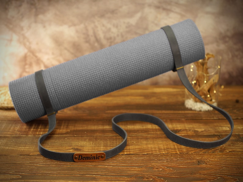 May include: A gray yoga mat with a brown leather strap and a personalized name tag that says "Dominic".