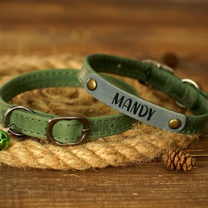 Puede incluir: Dos collares de perro de cuero verde con hebillas plateadas y cascabeles. El collar m&aacute;s grande tiene el nombre "Mandy" grabado en &eacute;l.