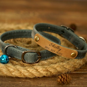 Puede incluir: Un collar de gato de cuero azul con una etiqueta de cuero marr&oacute;n que dice "Shelby 385-305-9685".