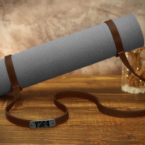May include: Gray yoga mat with a brown leather strap and a metal tag that says "Yoga".