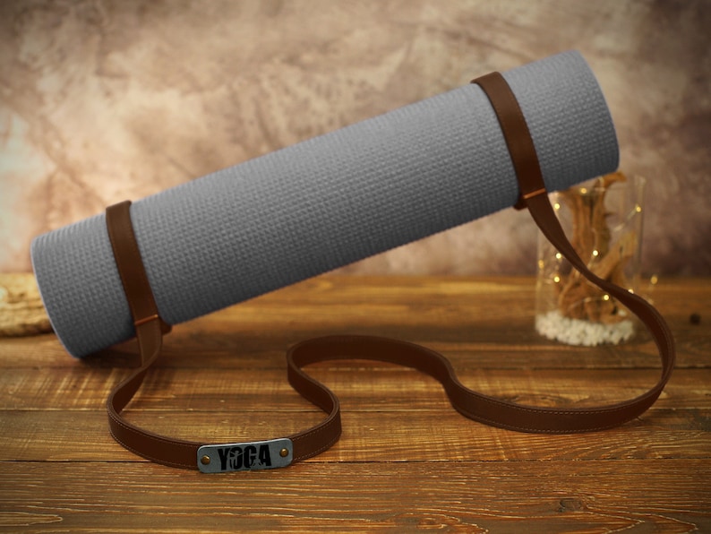 May include: Gray yoga mat with a brown leather strap and a metal tag that says "Yoga".