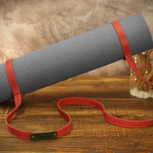 May include: A gray yoga mat with a red leather strap and a personalized name tag that says "Elizabeth".