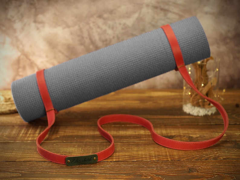 May include: A gray yoga mat with a red leather strap and a personalized name tag that says "Elizabeth".