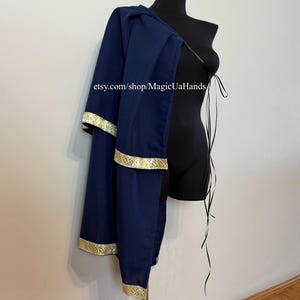 May include: A dark blue cape featuring a gold patterned trim along the edges and a black ribbon tie closure. The garment is displayed on a black mannequin. The text etsy.com/shop/MagicUaHands is visible on the fabric of the blue cape.