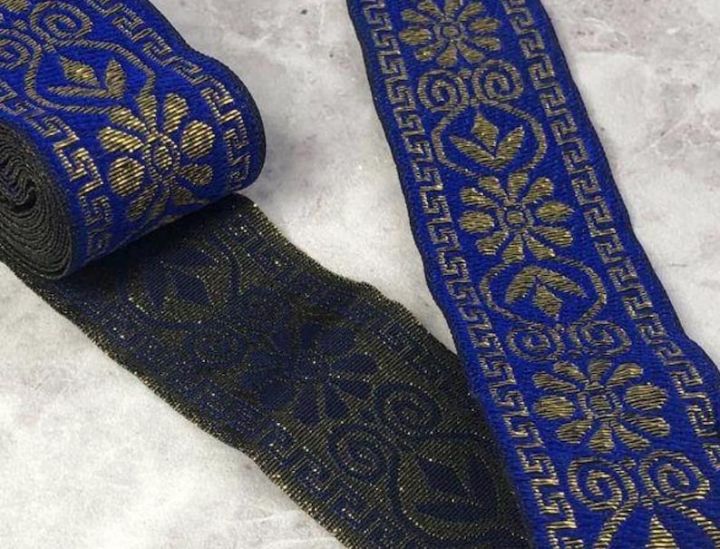May include: A roll of blue and gold decorative ribbon with a floral and geometric pattern. The ribbon is approximately 1 inch wide and features a metallic gold design on a dark blue background. The ribbon is suitable for various craft projects.
