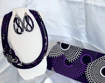 May include: A purple and black fabric clutch with a geometric pattern. A matching necklace and earrings are also included.