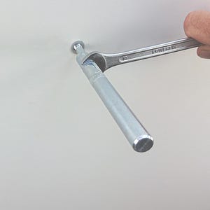 May include: A silver metal rod is being tightened with a wrench. The wrench is labeled "POWERFIX" and "10".