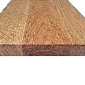 Pu&ograve; includere: Primo piano del bordo di una tavola di legno, che mostra la venatura del legno. La tavola &egrave; in rovere marrone chiaro e ha una finitura naturale.