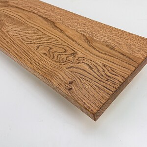 May include: A close-up of a wooden shelf with a natural wood finish. The shelf has a slightly curved edge and shows the natural grain of the wood.