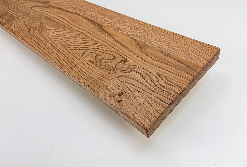May include: A close-up of a wooden shelf with a natural wood finish. The shelf has a slightly curved edge and shows the natural grain of the wood.