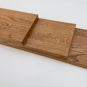 May include: Three pieces of unfinished, light brown wood planks stacked on top of each other. The wood has a natural grain pattern.
