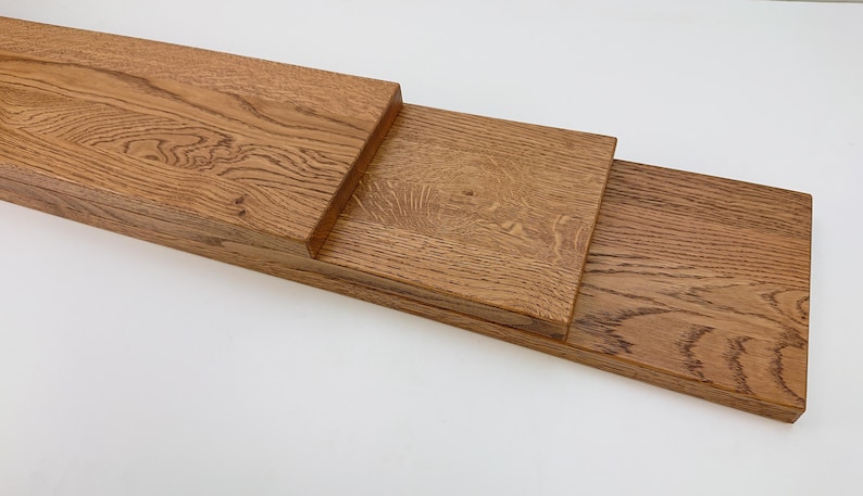 May include: Three pieces of unfinished, light brown wood planks stacked on top of each other. The wood has a natural grain pattern.