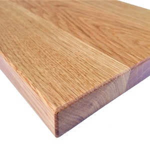 Pu&ograve; includere: Primo piano del bordo di un piano di lavoro in legno marrone chiaro. La venatura del legno &egrave; visibile e la superficie &egrave; liscia.
